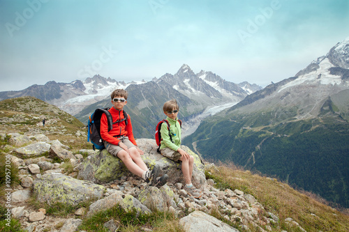 Two boys are sitting on slope of high mountain in the european Alps