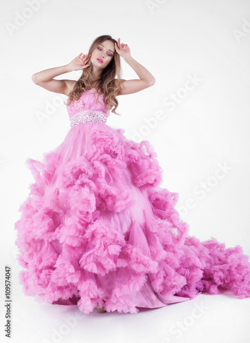 Portrait of sexy young beautiful caucasian blonde in gorgeous pink dress on white background