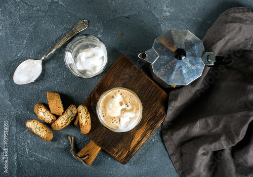 Glasses of coffee with ice cream on rustic wooden board, steel Italian Moka pot over grey concrete textured background photo