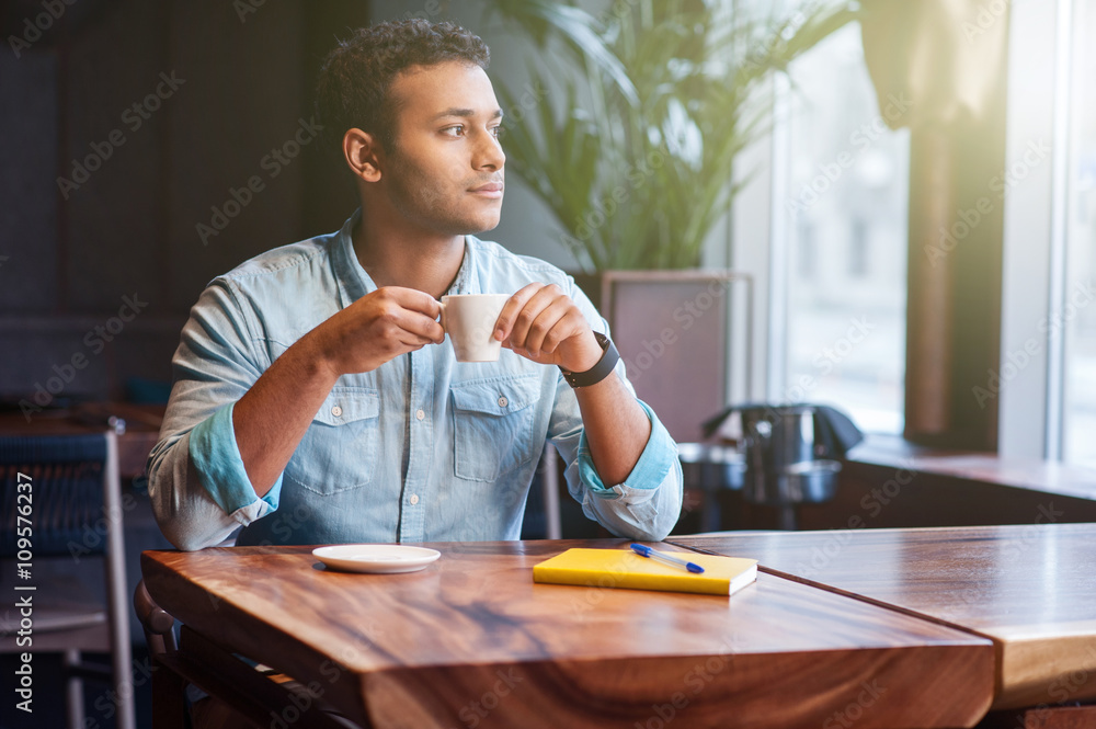 Attractive eastern guy is drinking hot beverage Attractive eastern guy is drinking hot beverage
