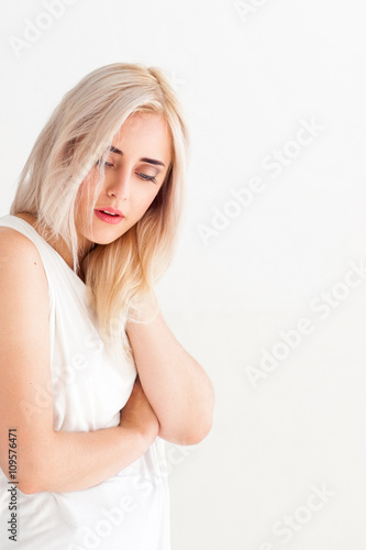 Woman with pain in neck on white background. Massage therapy of painful neck. Tired neck after long working hours. Woman relaxes the neck.