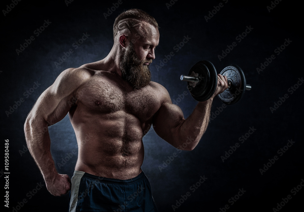 Power athletic bearded man in training pumping up muscles with d