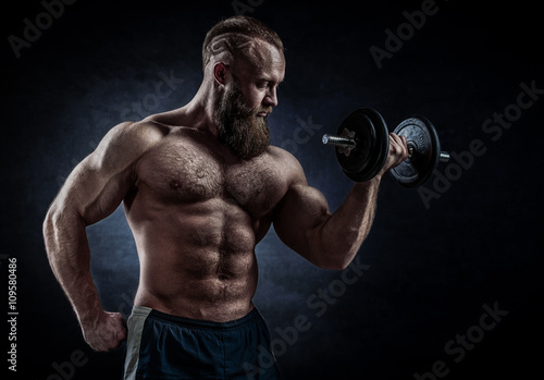 Power athletic bearded man in training pumping up muscles with d © FoodAndPhoto