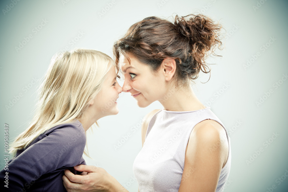 Beautiful brunette woman with young blond girl on grey background Beautiful brunette woman with young blond girl on grey background