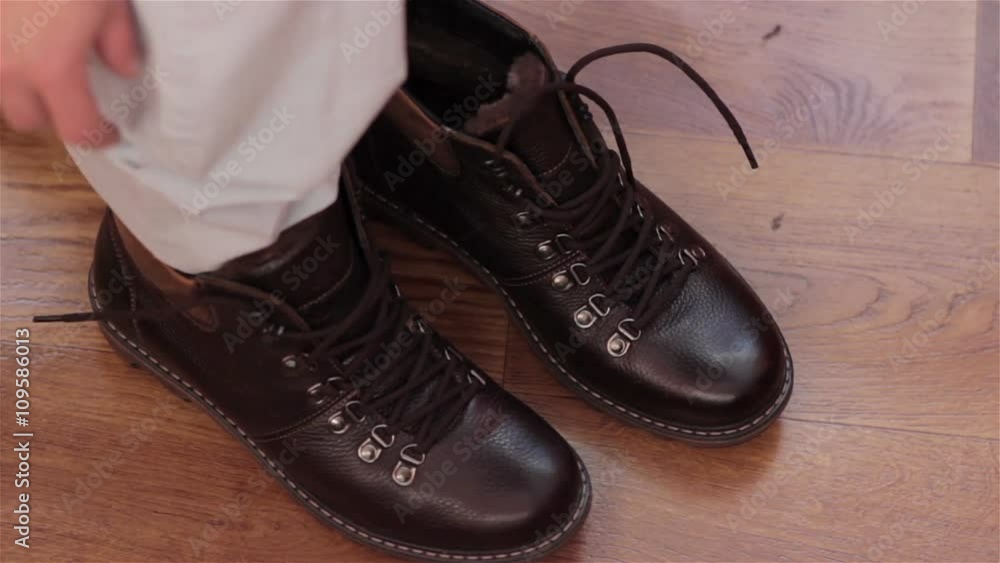 Man Putting On Boots/New classic boots put on the floor Man Putting On Boots/New classic boots put on the floor