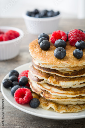 Pancakes with blueberries and raspberries on rustic wood

