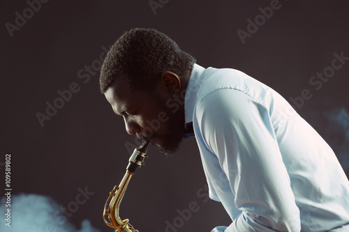 Canvas Print African American jazz musician playing the saxophone on grey background