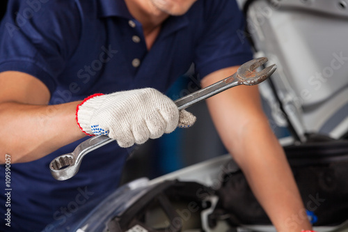 Mechanic Holding Wrench While Examining Car Engine