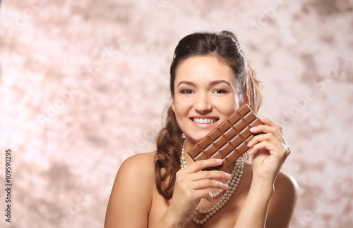 Portrait of beautiful young woman with chocolate on blurred background  close up