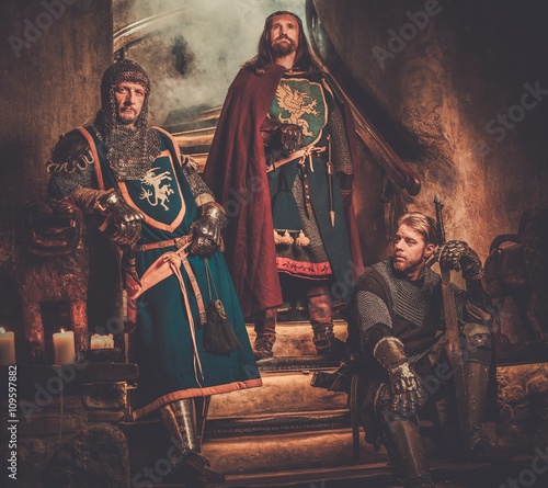 Medieval king with his knights in ancient castle interior.
