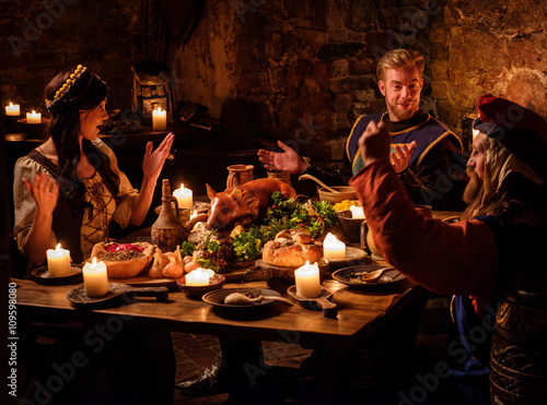 Medieval people eat and drink in ancient castle kitchen interior