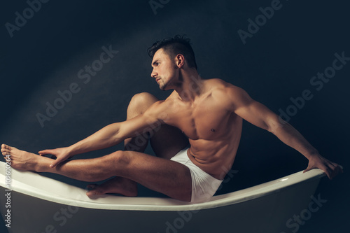 Muscular man on bathtub