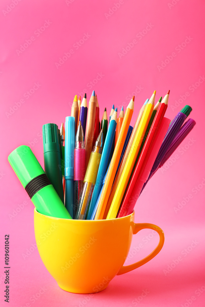 Fototapeta premium Colorful stationery in yellow cup on pink background