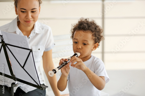 Tableau sur toile Young girl teaching little boy to playing on recorder