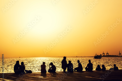 people relax on the waterfront at sunset