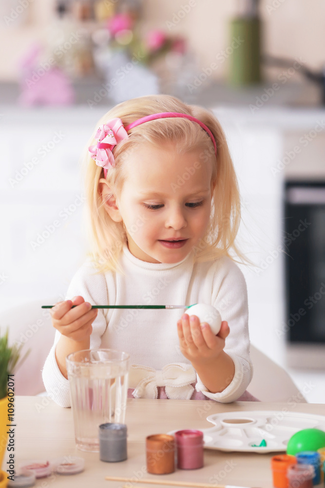 Little girl painting Easter eggs in the kitchen Little girl painting Easter eggs in the kitchen