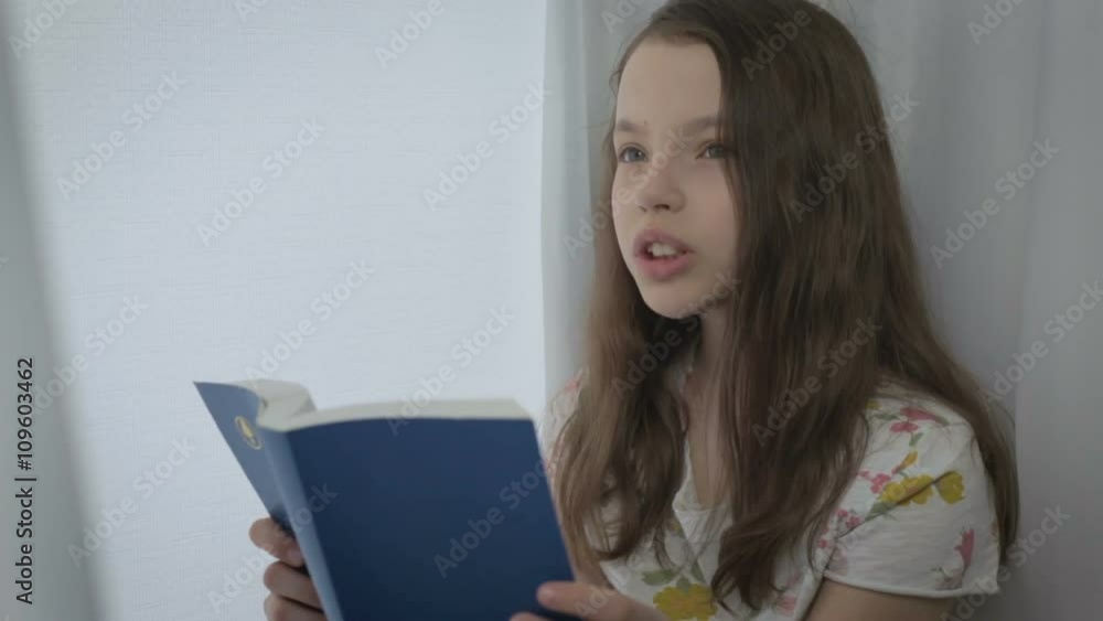 Beautiful little girl learns a poem by window. Beautiful little girl learns a poem by window.