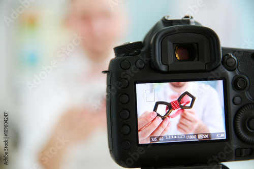 Young male blogger with tie bow on camera screen