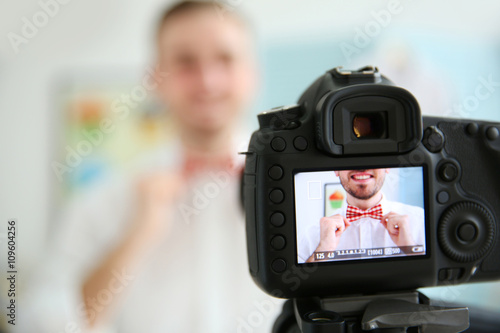Young male blogger with tie bow on camera screen © Africa Studio