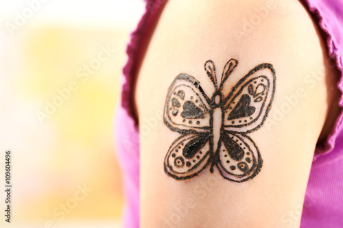 Image of butterfly painted with henna on girl's arm closeup photo