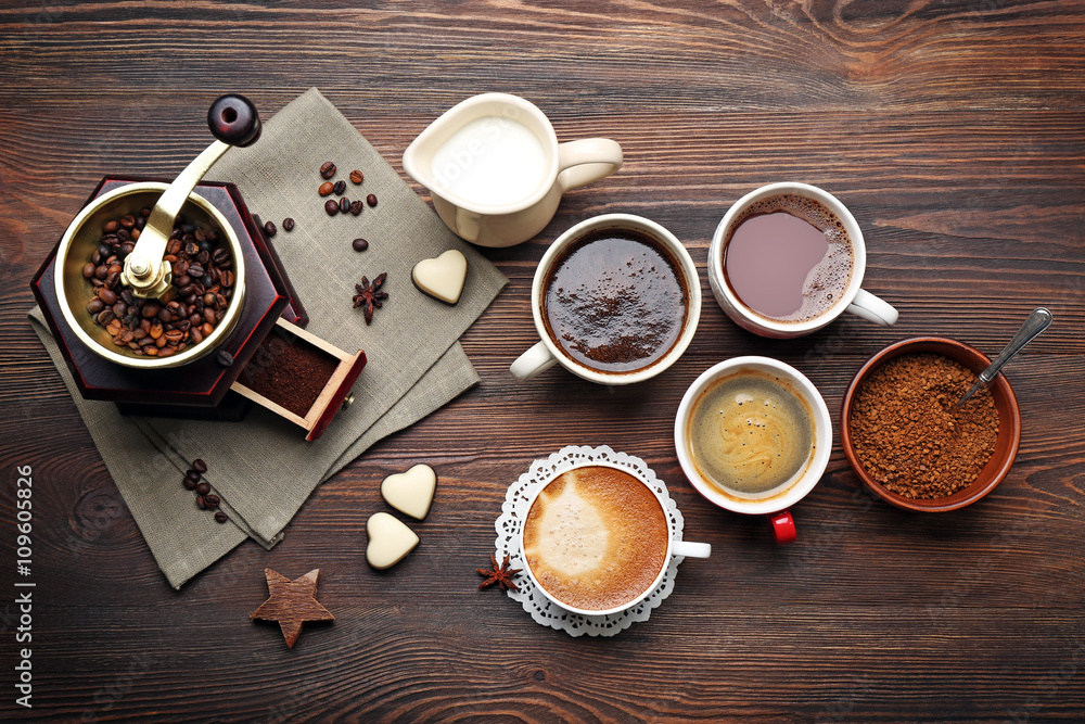 Cups of coffee with beans on wooden table, top view