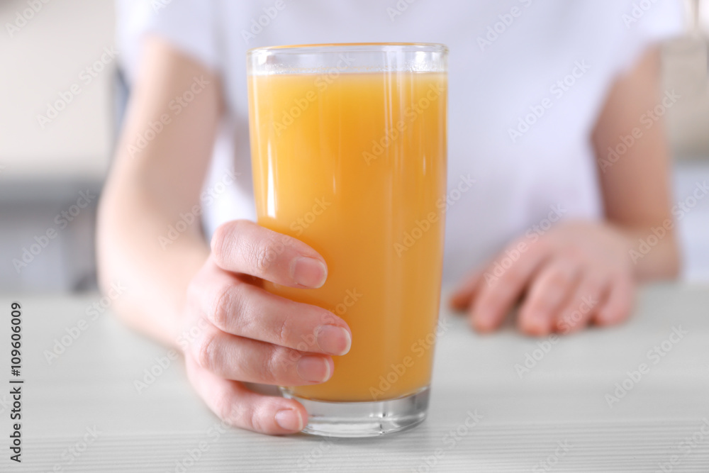 Female hand holding glass of orange juice on wooden table closeup Female hand holding glass of orange juice on wooden table closeup