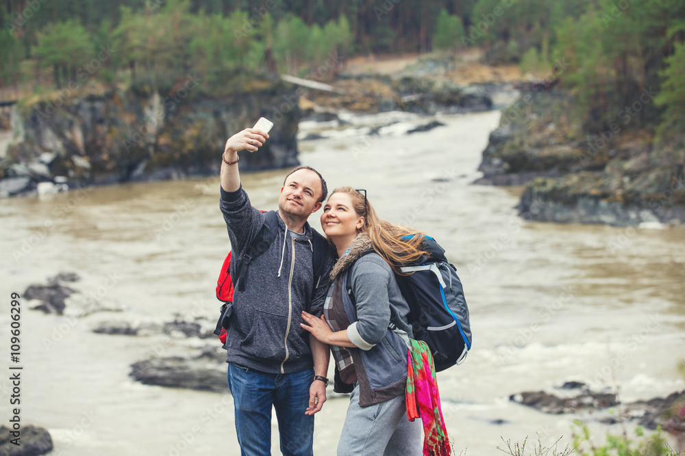 Young couple in the mountains with backpacks making selfie Young couple in the mountains with backpacks making selfie