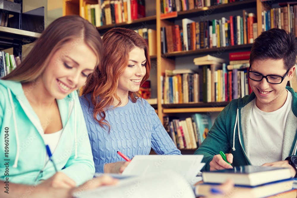 happy students writing to notebooks in library happy students writing to notebooks in library