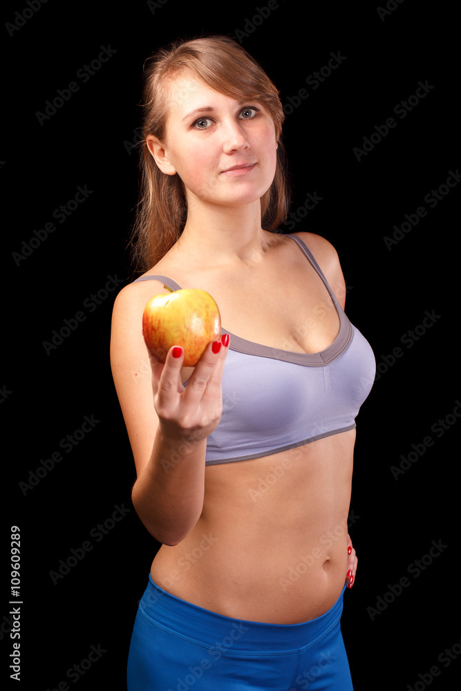 The girl who was engaged in sports, standing on a white background with an apple in his hand. The girl who was engaged in sports, standing on a white background with an apple in his hand.