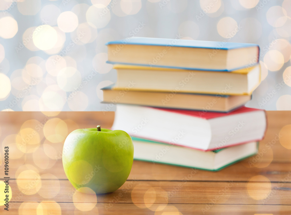 close up of books and green apple on wooden table