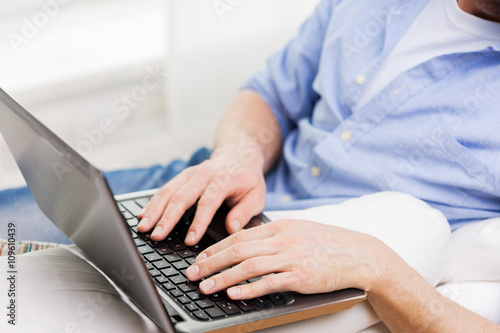 close up of man typing on laptop computer at home