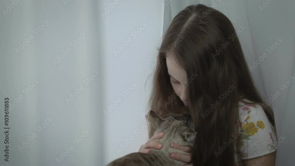 Beautiful little girl gently communicates with your loved cat at window. Beautiful little girl gently communicates with your loved cat at window.