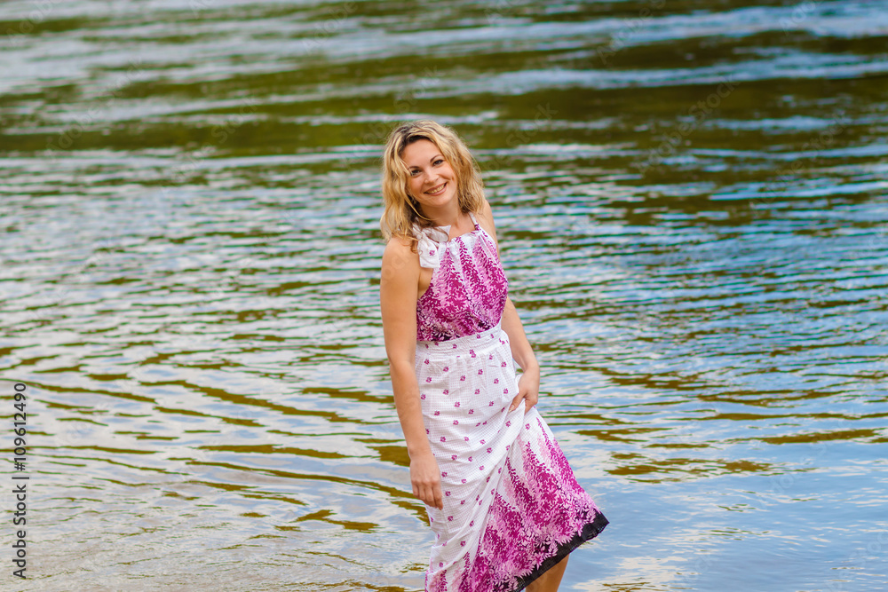 Woman in a long dress on the shore near the water Woman in a long dress on the shore near the water