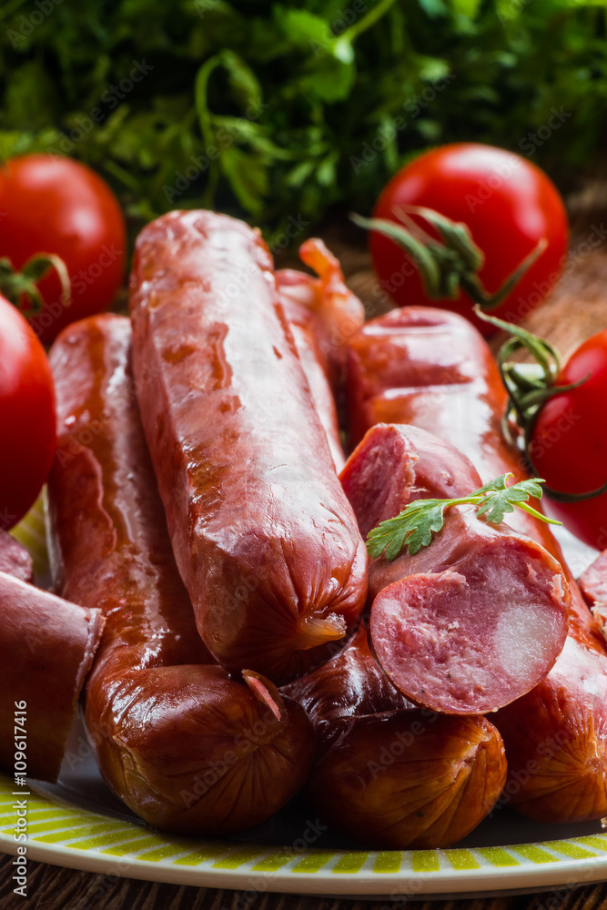 Smoked sausage and red ripe tomatoes on the kitchen table, selective focus
