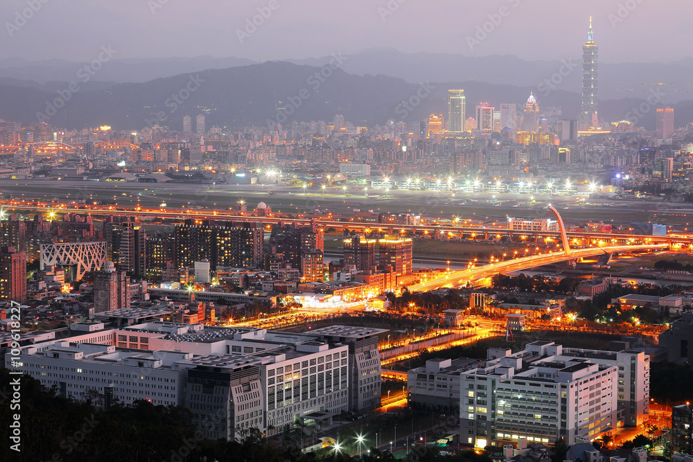 Panoramic aerial view of busy Taipei City, Keelung River, Dazhi Bridge, Songshan Airport & 101 Tower in XinYi District at dusk ~ A romantic evening of Taipei with beautiful blue twilight in the sky