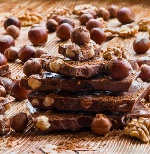Chocolate and nuts: hazelnuts and walnuts on a wooden background, selective focus