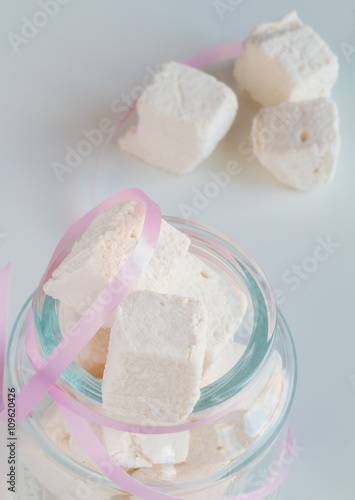 White marshmallows in glass jar on white table