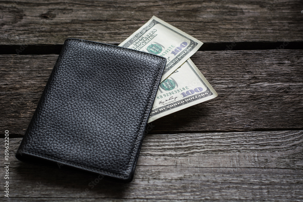 Black wallet and american dollar on wooden board. Black wallet and american dollar on wooden board.