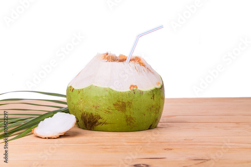 Refreshing green organic coconut fruit juice on wooden table