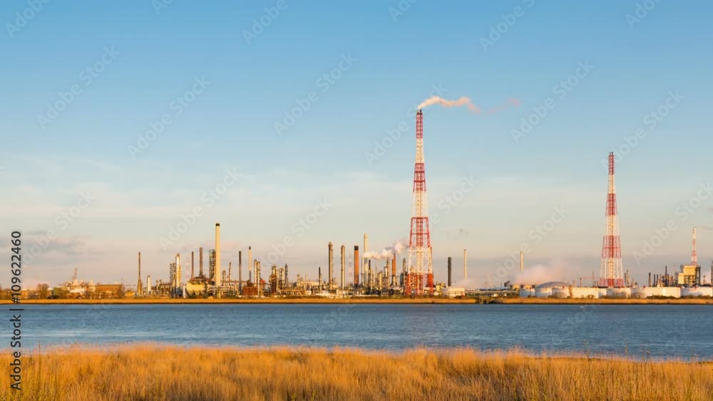 Panning timelapse sequence of a large oil refinery in the harbor of Antwerp, Belgium with blue sky and warm evening light. Panning timelapse sequence of a large oil refinery in the harbor of Antwerp, Belgium with blue sky and warm evening light.