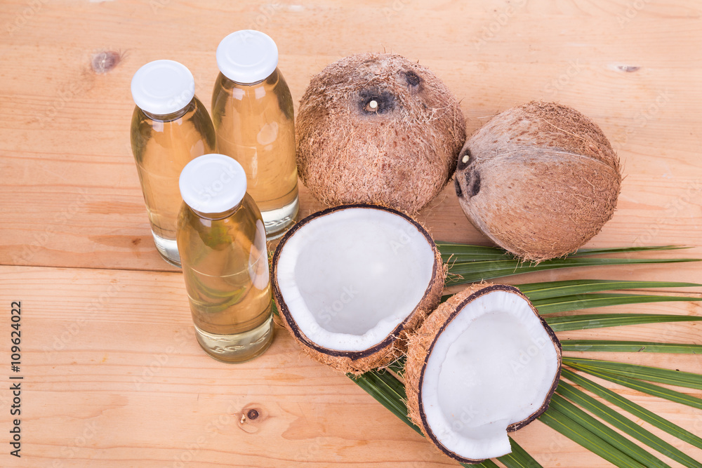 Three cold pressed extra virgin coconut oil in bottles with coconuts Three cold pressed extra virgin coconut oil in bottles with coconuts