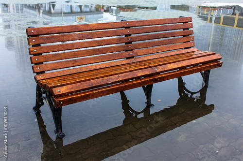 Wet bench with reflection in a puddle of Ekaterinburg city center
