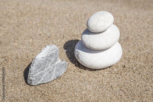heart shaped stone and stack of pebbles on balance on sand