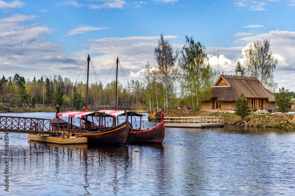 Wooden summerhouse on small island and sailing boats near small pier at river Daugava