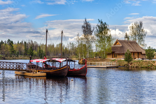 Wooden summerhouse on small island and sailing boats near small pier at river Daugava