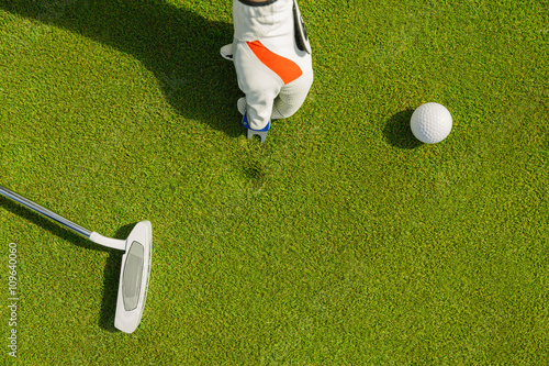 Male hand in glove marking ball position on the green. Focus on pitchmark