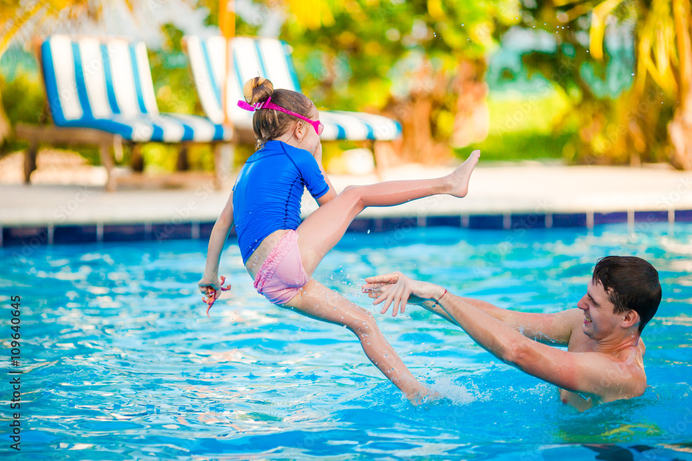 Little girl and happy father having fun in outdoors swimming pool
