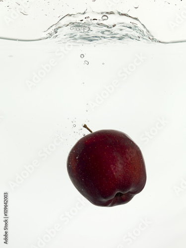 dropping red apple on clear water