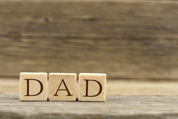 Wooden toy blocks spelling DAD with an old wooden background