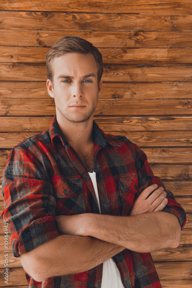 Obraz premium Handsome young man with crossed hands against wooden wall